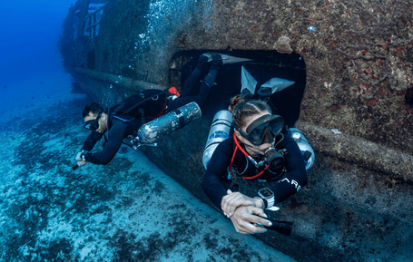 Two divers exiting a shipwreck.