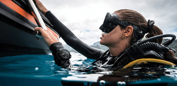 A diver holding onto the ladder on a boat