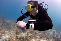 Diver underwater wearing an Oceanic O.i Wrist with its white wrist strap.